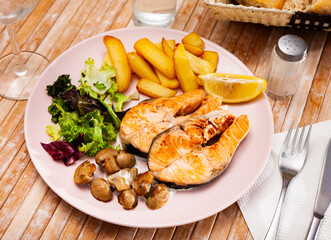 Fried salmon with fried potatoes and mushrooms served on plate