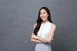 © Atstock Productions - Smiling young beautiful Asian businesswoman looking at camera and doing arm crossed gesture in isolated studio gray background