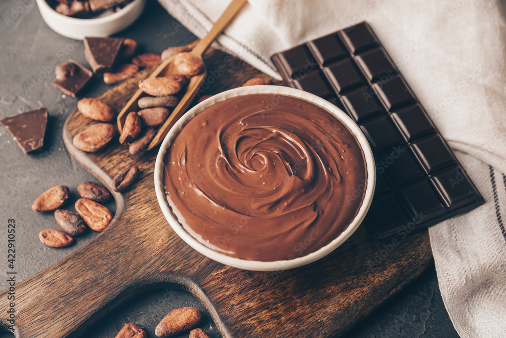 Bowl of tasty melted chocolate on dark background