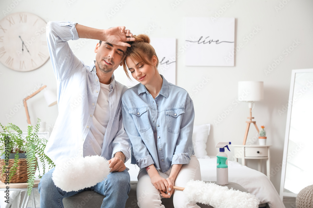 Young couple resting after cleaning their bedroom