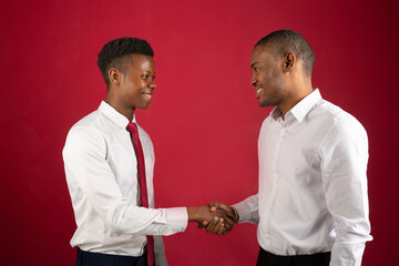 two handsome african men in white shirts shaking hands 