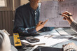 © amnaj - Architect man present a construction project point at the blueprint at the office.