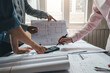 © amnaj - Close-up of a hand man architect to consult the collaboration using a calculator blueprint at the office.