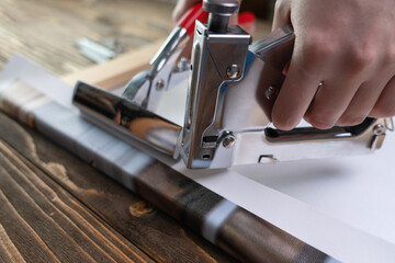 the process of stretching a synthetic canvas with a printed photo onto a wooden stretcher. hand with