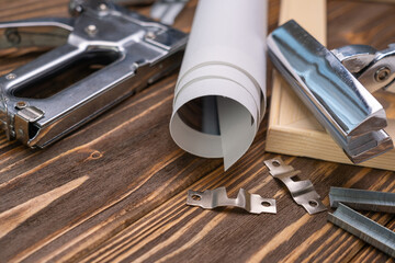 devices for stretching canvas on a wooden frame. stapler, canvas roll, wood frame and tensioning ton