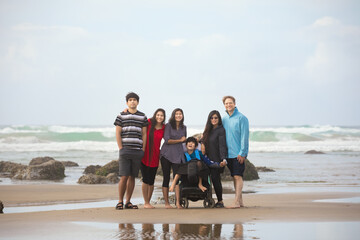 Biracial family of six together on the beach by ocean