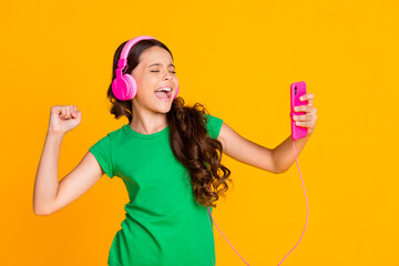 Sticker - Photo of happy excited smiling cheerful lovely girl enjoying listening music in headphones isolated on yellow color background