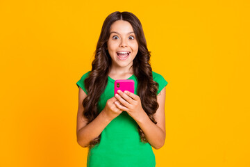 Poster - Photo of happy cheerful smiling lovely crazy girl see post comment in smartphone isolated on yellow color background