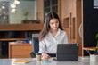 © amnaj - Beautiful Asian woman working on a tablet and taking notes at the office.
