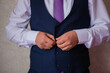 © Urmat - A man's hand buttons a three-piece suit.