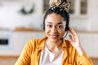© Kateryna - Close-up of African American an attractive confident young woman in headset, sitting in office, working as operator of call center or support service, looks directly at the camera and smiling friendly