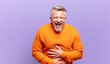 old senior man laughing out loud at some hilarious joke, feeling happy and cheerful, having fun