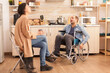 © DC Studio - Angry man in wheelchair because of emotional difficulties with wife in kitchen. Disabled husband arguing with spouse.