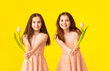 Poster - Portrait of cute twin girls with tulip flowers on color background