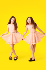 Wall Mural - Portrait of cute twin girls on color background