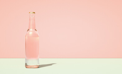 Leinwandbilder - Glass beer bottle on horizontally divided bi-color retro pastel pink and green color background.