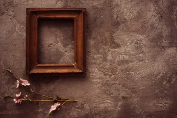 Vintage old wooden frame with spring flowers and leaves on dark rustic wooden background. Spring flowers composition with copy space.