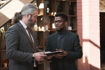 Wall Mural - Two businessmen talking to each other and using tablet pc before meeting in the restaurant