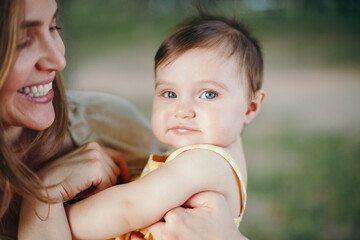 Mothers Day. Middle age smiling Caucasian mother and girl toddler daughter playing in park. Mom embracing hugging child baby on summer day outdoor. Authentic happy family childhood lifestyle.