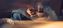 A Male Artisan In A Pottery Workshop Makes A Piece Of Clay Behind A Pottery Wheel. Traditional Pottery Craft.