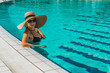 © Maksym - Girl travelling. Young sexy woman in Sun hat, bikini swimsuit, sunglasses swim in blue pool water. Straw hat on head. On resort, holiday, vacation.