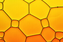 Bright Hot Background Closeup Of Oil Drops In Water. Abstract Art Macro Photo Of Liquid Surface With Gradient Yellow And Orange Bubbles.