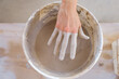 © Erika Anes/ADDICTIVE STOCK - From above crop anonymous craftswoman standing near table and pulling dirty hand from bucket filled with clay in studio in daylight
