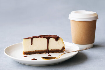 Wall Mural - Slice of cheesecake poured chocolate sauce on plate and disposable coffee container. Sweet delicious and hot drink. Coffee time concept.