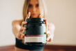 © Jake Jakab/ADDICTIVE STOCK - Blurred anonymous female wearing activewear with sports nutrition jar for body building in hands standing in room during training at home