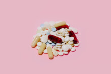 Pile Of Assorted Multicolored Capsules And Pills Of Different Sizes Placed On Pink Background