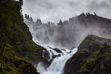 Spectacular Landscape Of Rapid River Streaming Between Rough Rocks In Mountains Of Norway On Cloudy Day