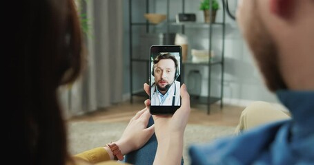 Couple man and woman in medical app on smartphone consulting with doctor via video conference on smartphone. Online chat to talk with family therapist during coronavirus pandemic, medic concept