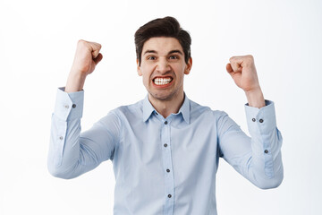 Successful corporate man, ceo manager celebrating, rejoicing saying yes and fist pump, triumphing standing over white background