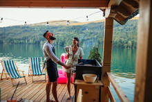 Young Couple Preparing A Meal At The Wooden Pier Near Lake