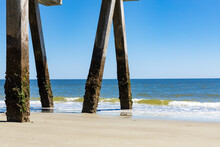 Barnacle Covered Concrete Pier Pilings By Blue Ocean Waters, Bright Blue Sky, Horizontal Aspect