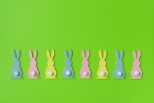 Easter Holiday Minimal Concept. Row Of Decorative Multicolored Easter Bunnies Isolated On Green Background. Creative Flat Lay. For Design Cards Or Web Banners. Copy Space