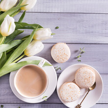 Morning Cup Of Coffee, Cake Macaron And Spring Tulip Whate Flowers On White Wooden Background. Flat Lay.Beautiful Breakfast For Women
