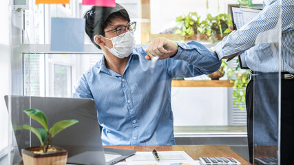 Aufkleber - Two business colleagues greet each other by bumping elbows when meeting in office while wearing face mask