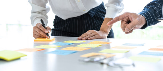 Poster - Two creative business people meeting and planning use post it notes sticky note on desk to share idea, Analysis data chart and graph with teamwork strategy brainstorming in office