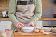 © Ladanifer - Unrecognizable young woman cracking or breaking an egg. Cooking time.