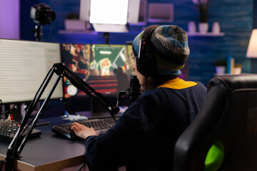 Canvas Print - Professional streamer playing shooter games wearing headphones and talking into microphone via streaming chat. Gamer making online videogames with new graphics on powerful computer