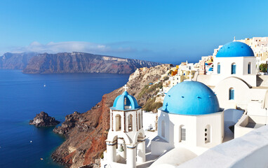 Greece. Santorini Island. Oia village. The Orthodox Church with the traditional blue domes and white plastered walls  and blue water of the Aegean Sea