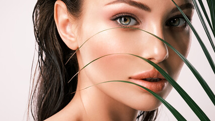 Wall Mural - young beautiful woman with green leaves near face. skin care beauty treatments concept. closeup girl