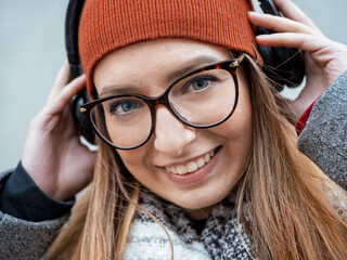 close-up portrait of a beautiful girl with poor eyesight in headphones on a gray background