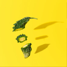 Karela Cut In Three Pieces  On Bright Yellow Background.