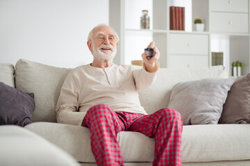 Wall Mural - Photo of aged man pensioner happy positive smile sit couch home watch tv cinema switch channel remote controller