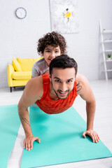 Wall Mural - Smiling muslim man doing press ups with son on back