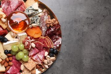 Plate of different appetizers with honey on grey table, top view. Space for text