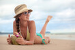 © el.rudakova - Young woman laying on beach and drinking coconut milk