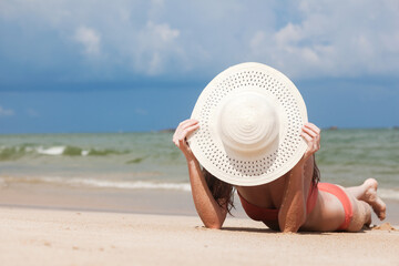 Wall Mural - Beautiful woman in bikini and straw hat sunbathing at the seaside